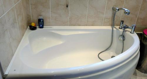 a white bath tub with a shower in a bathroom at 6 Mulberry Lea, Upwell, Norfolk in Upwell