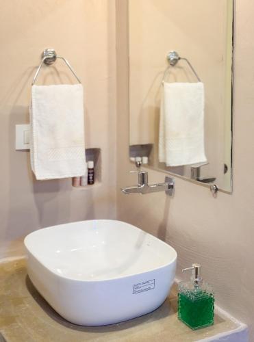 a sink in a bathroom with a mirror and towels at Bay Village Inn in Arambol