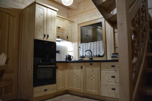 a kitchen with wooden cabinets and a sink and a microwave at Królowo Chatka Na Budzu in Czerwienne