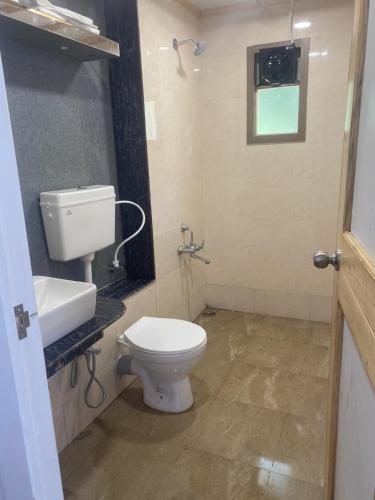 a bathroom with a toilet and a sink and a window at Stay NC Eco Cottages in Nashik
