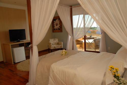 1 dormitorio con 1 cama con cortinas y TV en Ramada by Wyndham Furnaspark, en Formiga