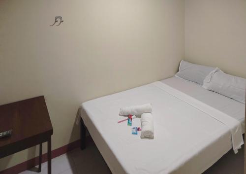 a white bed with two towels and a table at RM Dormitel by RedDoorz in Butuan