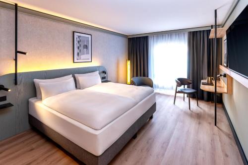 a hotel room with a bed and a desk at Radisson Hotel Düsseldorf City Center in Düsseldorf