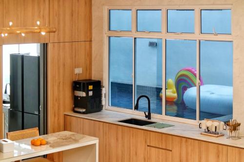 a kitchen with a sink and a large window at Desaru 918 Muji Villa in Bandar Penawar