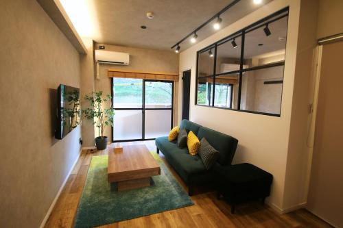 a living room with a green couch and a table at 三の丸Stay 202号室 in Kumamoto