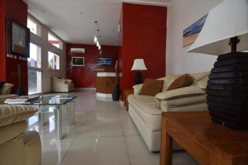 una sala de estar con muebles blancos y paredes rojas. en Hotel Ophelia Lodge, en Port-Gentil