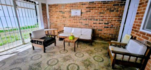 ein Wohnzimmer mit Stühlen und einer Ziegelwand in der Unterkunft El Corazón de Villa in Villa del Carbón