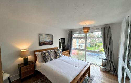 Un dormitorio con una cama y una ventana grande. en Weybridge Stunning Five Bedroom House With Garden, en Oatlands Park