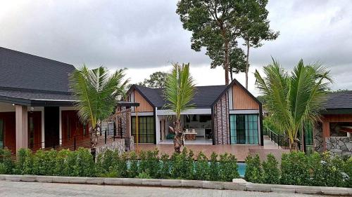 a house with palm trees in front of it at Naisuan villa 
