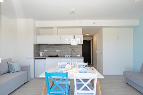 a kitchen and a living room with a table and chairs at Kolory Lata - 365PAM KLIMATYZACJA I PLAC ZABAW W OBIEKCIE in Sarbinowo