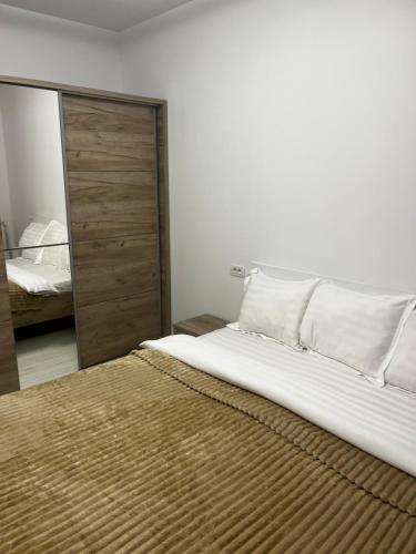 a bedroom with a large white bed and a mirror at The Lakehouse Snagov Near Therme in Vlădiceasca