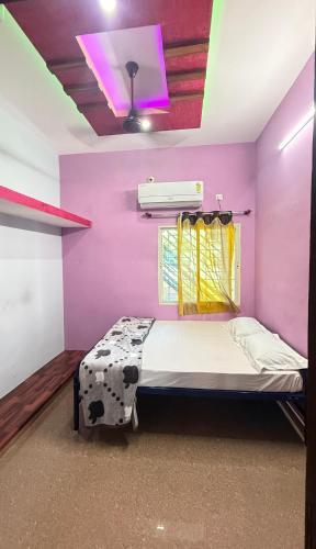 a bedroom with a bed with a pink wall at NAKSHATHRA Guest House 2BHK in Tiruvannāmalai