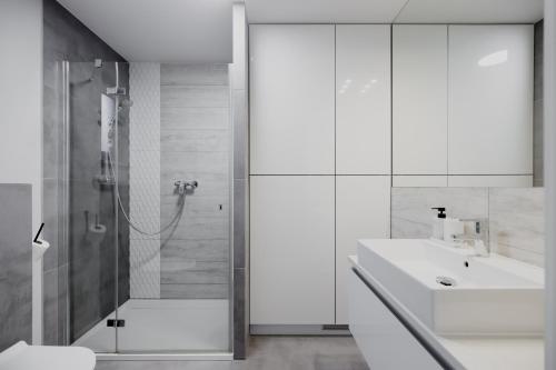a white bathroom with a sink and a shower at Trzy Wyspy Barlinek in Barlinek