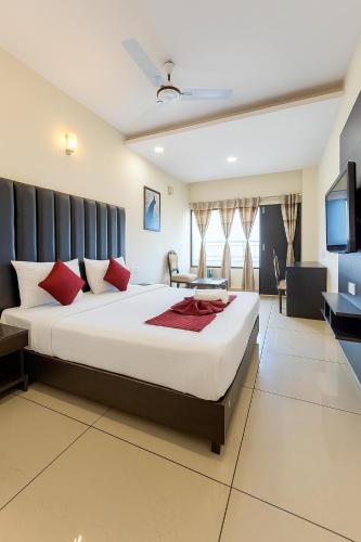 a bedroom with a large white bed with red pillows at Hotel JB Residency Zirakpur Chandigarh # Large Rooms # Balcony Rooms # Top Rated in Zirakpur