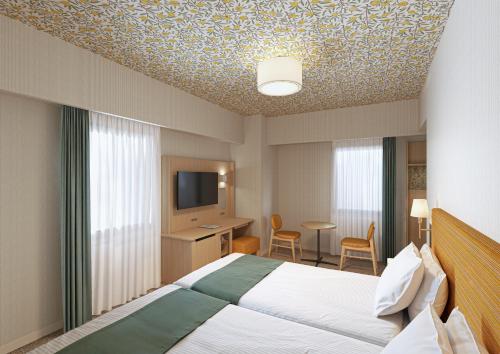 ein Hotelzimmer mit einem Bett und einem Flachbildfernseher in der Unterkunft Hotel Monterey La Soeur Naha in Naha