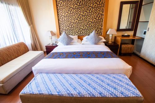 a hotel room with two beds and a couch at Natya Hotel Tanah Lot in Tanah Lot