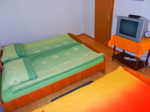 a room with two beds and a tv and a table at Gostilna Stara Pošta in Pucaie