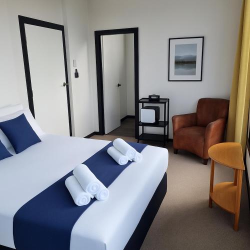 a hotel room with a bed and a chair at The Old Railway Hotel Lumsden in Lumsden