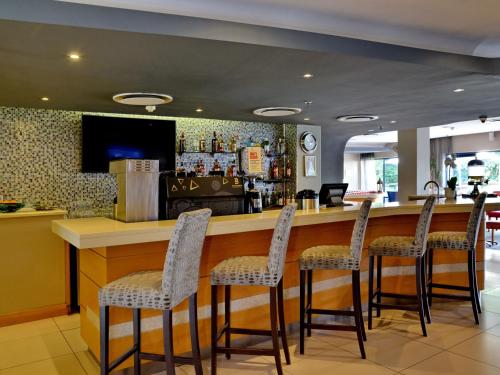 a bar in a restaurant with four stools at ANEW Hotel Roodepoort Johannesburg in Roodepoort