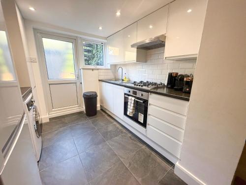 a kitchen with white cabinets and a stove top oven at 1-Bedroom flat with small garden & Paid Parking in Finsbury Park, Highbury in London