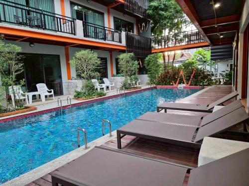 a swimming pool with chaise lounges next to a building at WOW PHUKET in Phuket Town
