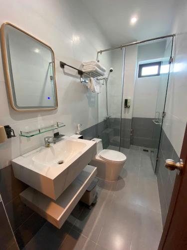 a bathroom with a sink and a toilet and a mirror at Hoàng Long Hotel in Chợ Phước Hải