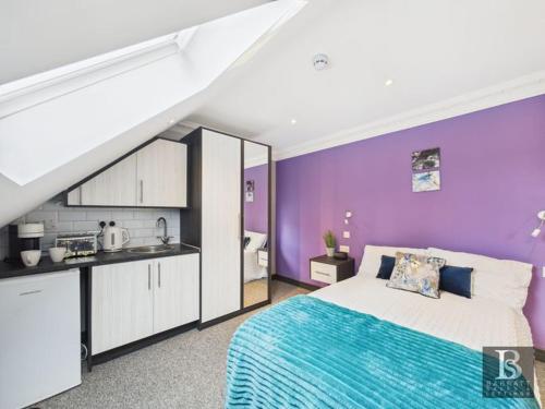 a purple bedroom with a bed and a kitchen at Luxury room's with ensuite and kitchen, parking in Slough Centre in Slough