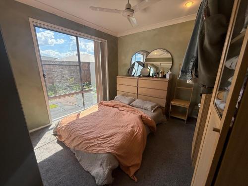 een slaapkamer met een bed en een groot raam bij The Atelier Artful Home Stay at Mangohill in North Lakes