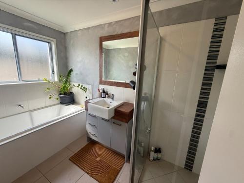 een badkamer met een wastafel, een bad en een douche bij The Atelier Artful Home Stay at Mangohill in North Lakes