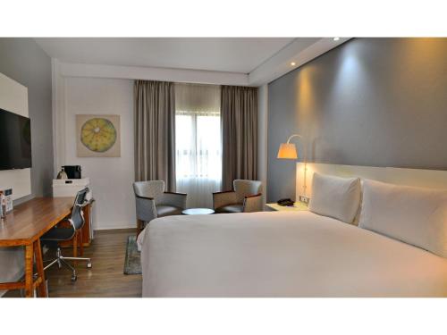 a hotel room with a large bed and a desk at ANEW Hotel Roodepoort Johannesburg in Roodepoort