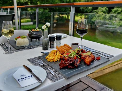 a table with a plate of food and two glasses of wine at ANEW Hotel Roodepoort Johannesburg in Roodepoort