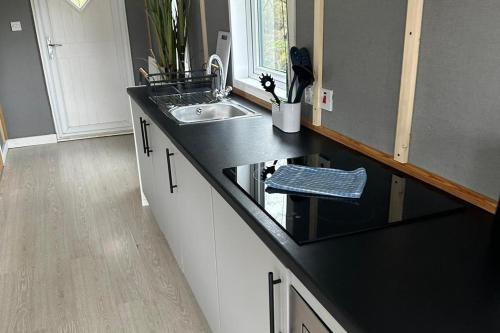 a kitchen with a sink and a black counter top at Glamping Hut - Sleeps up to 4 Hot Tub & Parking in Welshpool