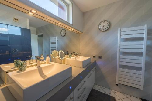 ein Badezimmer mit zwei Waschbecken und einem großen Spiegel in der Unterkunft Le Cristal - Prestigieux appartement au Lac d'Annecy in Doussard
