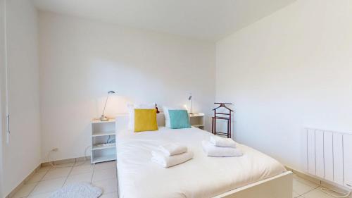 een witte slaapkamer met een bed met handdoeken erop bij Parenthèse à Eguisheim in Eguisheim