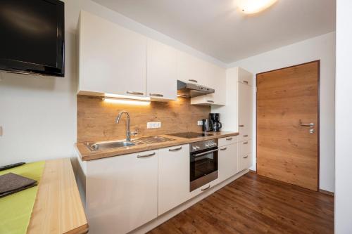 a kitchen with white cabinets and a sink at Aparthotel am Reitecksee in Flachau