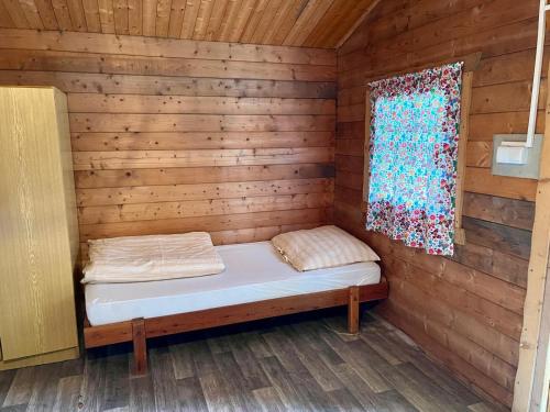 a bed in a wooden cabin with a window at ATC Kemp Kajlovec in Hradec nad Moravici