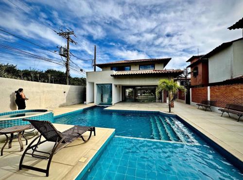 a person taking a picture of a swimming pool in a house at Casa Praia Marina Búzios in Búzios