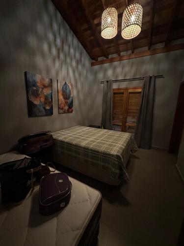 a room with two beds and a bag on a table at Rancho Recanto dos Pássaros in Limeira