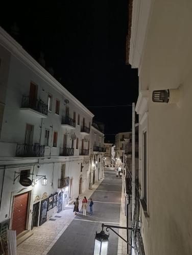 an alley with people walking down a street at night at Domus MiTo in Monte SantʼAngelo