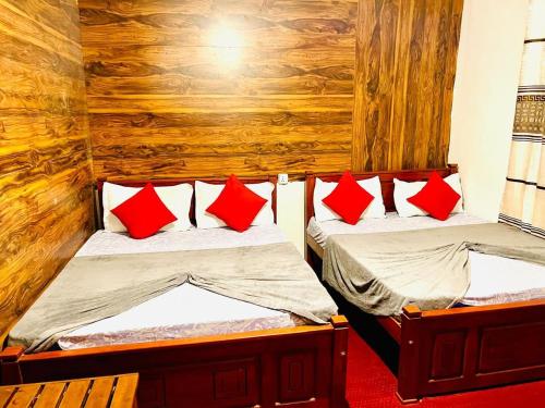 two twin beds in a room with red pillows at Kithaya Ella in Ella