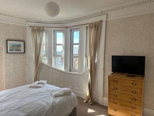 a bedroom with a bed and a television on a dresser at Crawford House in Largs