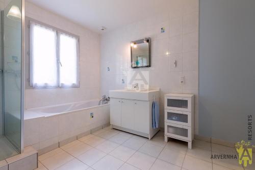 un bagno con vasca, lavandino e specchio di Chalet Flore a Murol