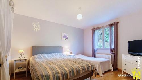 una camera da letto con un letto e una TV a schermo piatto di Chalet Flore a Murol