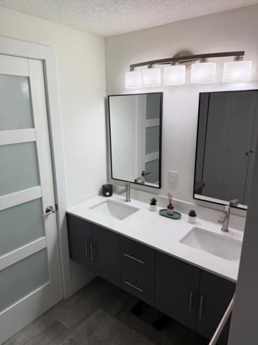 a bathroom with two sinks and two mirrors at Beach Front Condo In Paradise Marco Island in Marco Island
