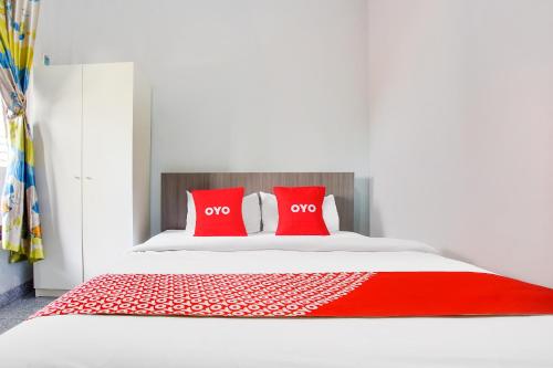 a white bed with two red pillows on it at Dancenter Z Hotel in Bandar Lampung