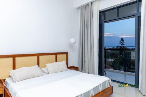 a bedroom with a bed and a large window at Ikamba-Lakeview Apartment in Kampala