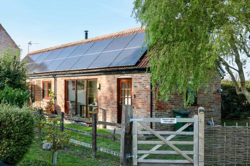 a brick cottage with solar panels on the roof at Tranquil and cosy cottage on the Somerset Levels in Bridgwater