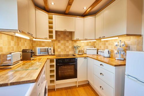 eine Küche mit weißen Schränken und Arbeitsflächen aus Holz in der Unterkunft Host & Stay - Dairy Cottages in Masham
