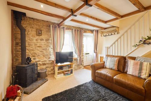 ein Wohnzimmer mit einem Ledersofa und einem Kamin in der Unterkunft Host & Stay - Dairy Cottages in Masham