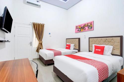 a hotel room with two beds and a flat screen tv at Dancenter Griya Bawean in Tanjungkarang
